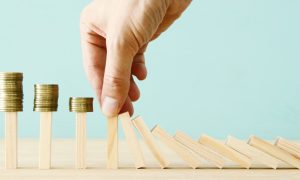 Image representing responsible gambling with a hand stopping the domino from falling for a story about problem gambling calls stemming from skill games increasing.