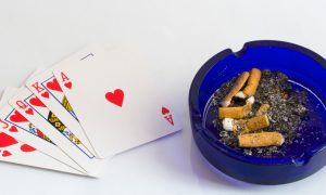 Image showing cigarettes in an ashtray and casino playing cards for a story about influencer Brian Christopher pushing for a smoking ban at Pennsylvania casinos.